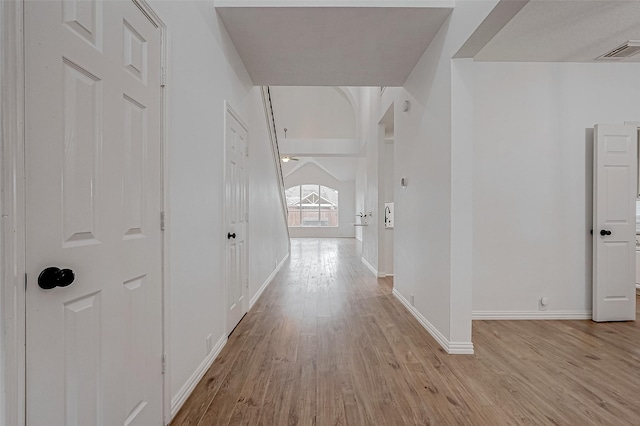 corridor with vaulted ceiling and light hardwood / wood-style floors