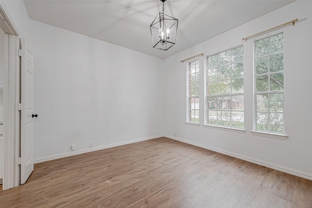 empty room featuring wood-type flooring and a chandelier