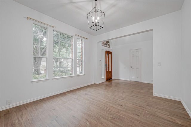 spare room with a notable chandelier and wood-type flooring