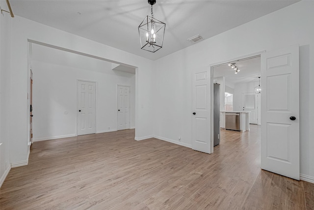 unfurnished dining area with an inviting chandelier and light wood-type flooring