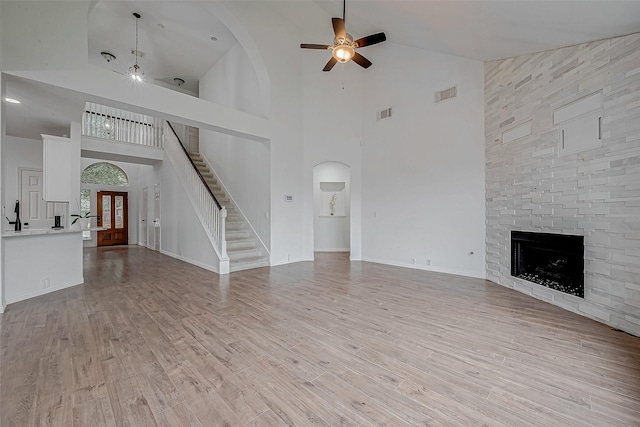 unfurnished living room featuring ceiling fan, a fireplace, vaulted ceiling, and light wood-type flooring