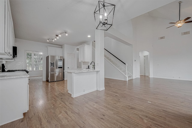 kitchen featuring white cabinetry, backsplash, hanging light fixtures, light hardwood / wood-style floors, and stainless steel fridge with ice dispenser