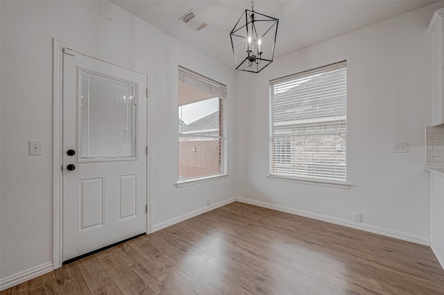 unfurnished dining area featuring a chandelier and light wood-type flooring