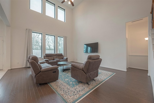 living room with a high ceiling, ceiling fan, and dark hardwood / wood-style flooring