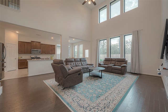 living room featuring a high ceiling, hardwood / wood-style floors, and ceiling fan