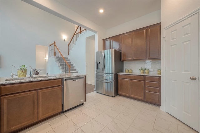 kitchen with tasteful backsplash, sink, light stone countertops, and appliances with stainless steel finishes