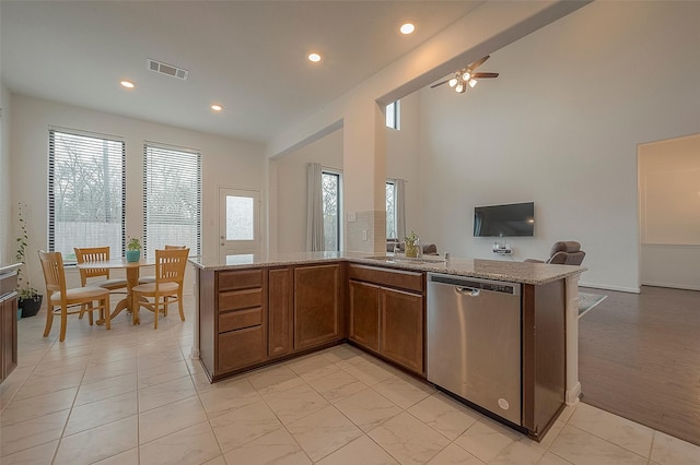 kitchen with dishwasher, kitchen peninsula, and light stone countertops