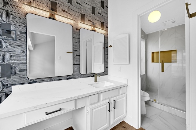 bathroom featuring a shower with door, vanity, and toilet