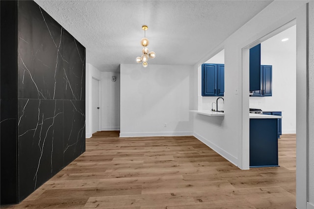 unfurnished dining area featuring light wood-type flooring, sink, and a textured ceiling