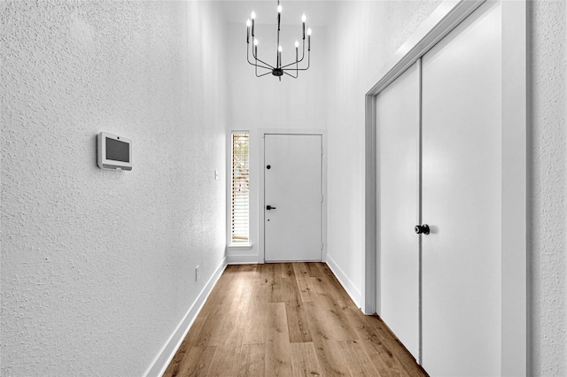 doorway featuring a chandelier, light hardwood / wood-style floors, and a high ceiling