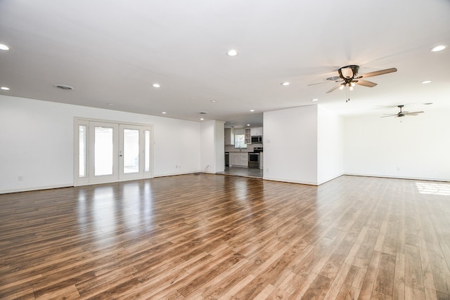 unfurnished living room featuring hardwood / wood-style floors, ceiling fan, and french doors