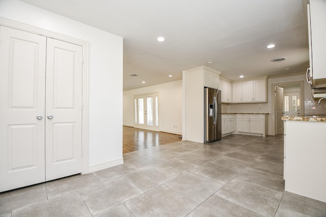 kitchen featuring tasteful backsplash, sink, white cabinets, stainless steel fridge, and light stone counters