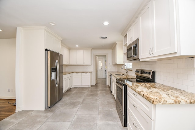 kitchen featuring sink, light stone counters, tasteful backsplash, stainless steel appliances, and white cabinets