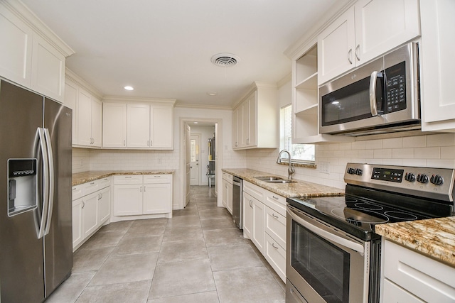 kitchen featuring appliances with stainless steel finishes, sink, white cabinets, decorative backsplash, and light stone counters