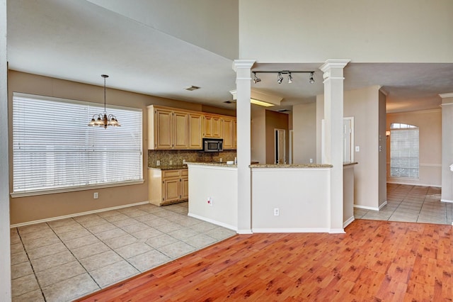 12726 Silverglen Estates Dr, Houston, TX 77014 - kitchen featuring light wood-style floors, ornate columns, light brown cabinetry, stainless steel microwave, and backsplash