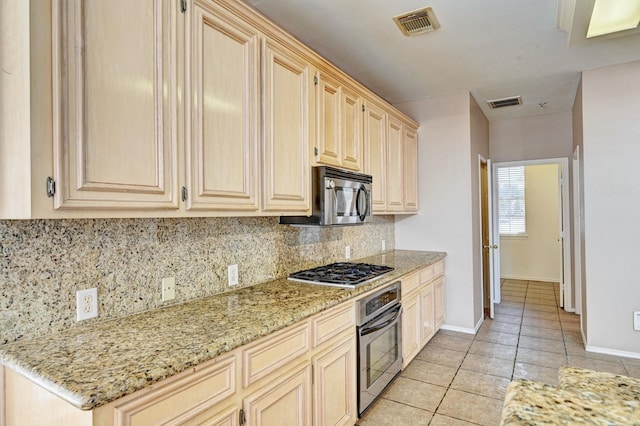 kitchen with light stone counters, light tile patterned floors, decorative backsplash, and stainless steel appliances