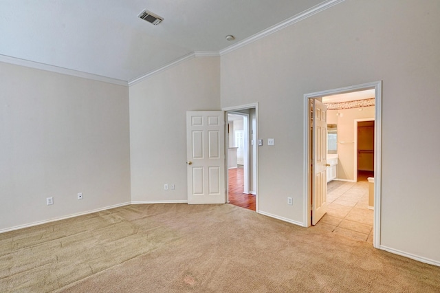 carpeted empty room with ornamental molding and vaulted ceiling