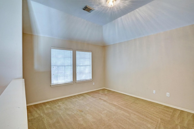 empty room featuring light colored carpet and lofted ceiling