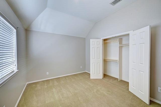 unfurnished bedroom featuring vaulted ceiling, light colored carpet, and a closet