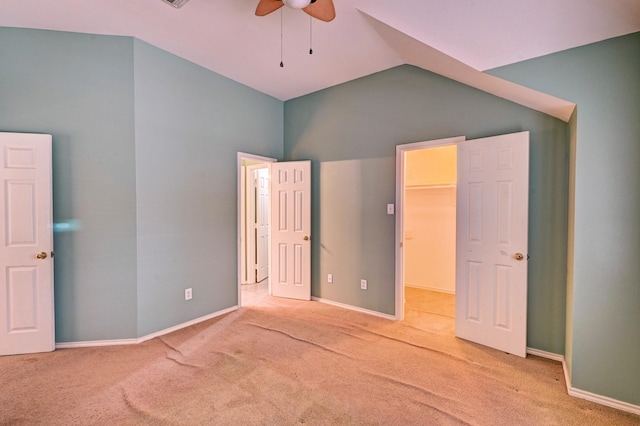 unfurnished bedroom featuring ceiling fan, a walk in closet, vaulted ceiling, and light carpet