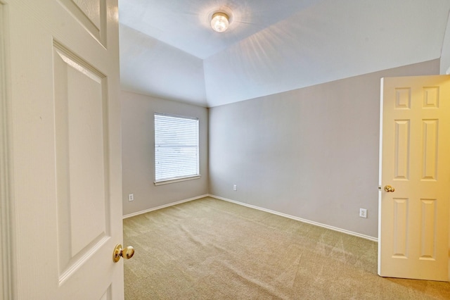 carpeted spare room with vaulted ceiling