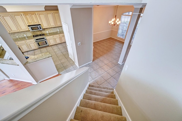 staircase with tile patterned flooring and a notable chandelier