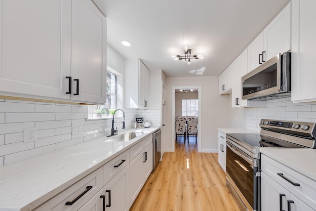 kitchen with appliances with stainless steel finishes, sink, and white cabinets