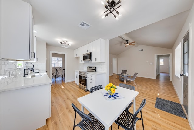 dining space with sink, light hardwood / wood-style flooring, ceiling fan, and vaulted ceiling