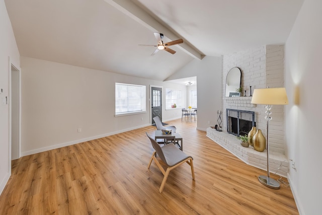 living room featuring vaulted ceiling with beams, ceiling fan, a fireplace, and light wood-type flooring