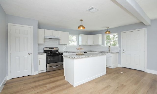 kitchen featuring hanging light fixtures, stainless steel gas range oven, and white cabinetry