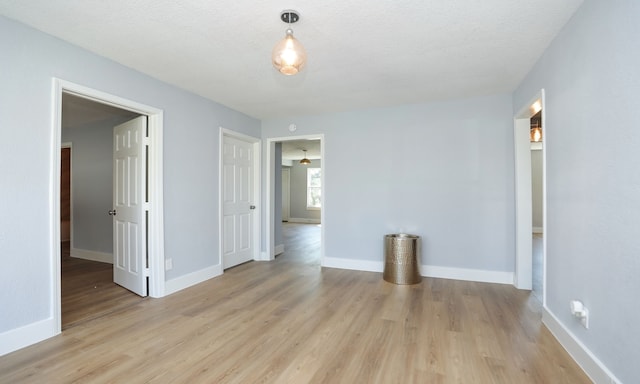 unfurnished room featuring a textured ceiling and light hardwood / wood-style flooring