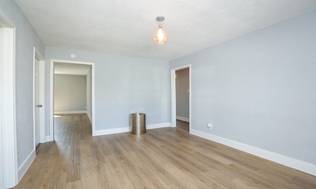 empty room with light hardwood / wood-style floors and a textured ceiling