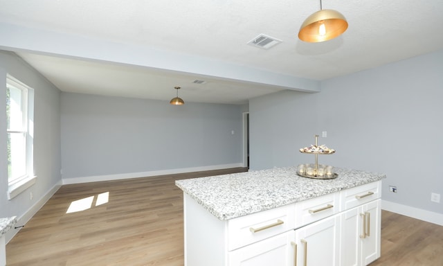 kitchen with a center island, light hardwood / wood-style flooring, pendant lighting, light stone countertops, and white cabinets