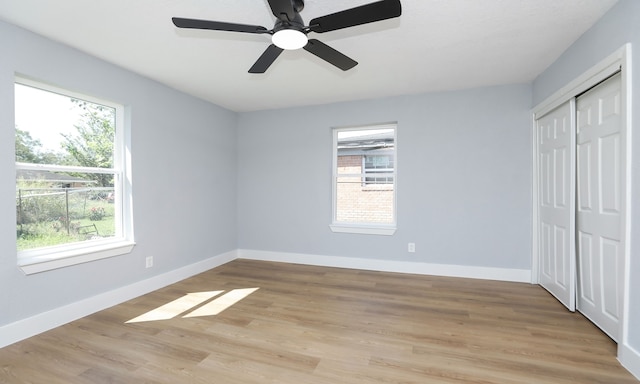 unfurnished bedroom with multiple windows, light hardwood / wood-style flooring, a closet, and ceiling fan