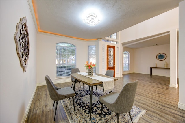 dining space featuring wood-type flooring and a textured ceiling