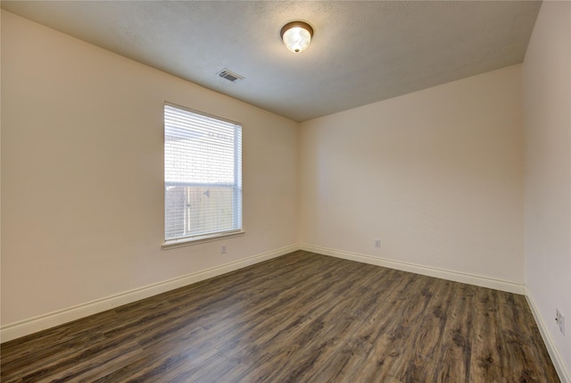 empty room with dark hardwood / wood-style floors and a textured ceiling