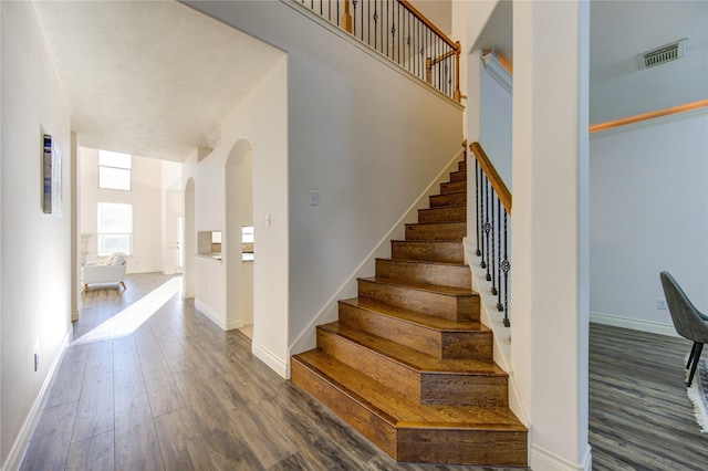 stairway featuring hardwood / wood-style floors and a high ceiling