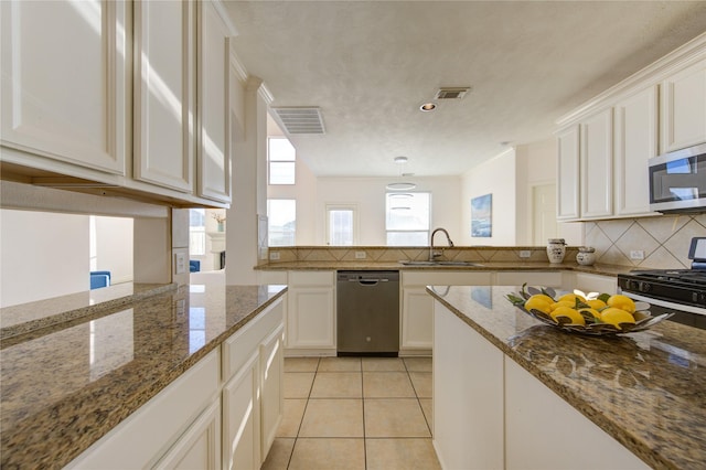 kitchen featuring dark stone countertops, white cabinetry, stainless steel appliances, tasteful backsplash, and light tile patterned flooring