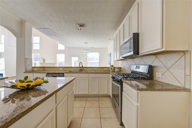 kitchen featuring sink, tasteful backsplash, stone countertops, light tile patterned floors, and stainless steel appliances