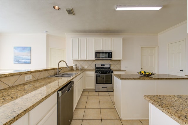 kitchen featuring light tile patterned flooring, appliances with stainless steel finishes, white cabinetry, sink, and decorative backsplash