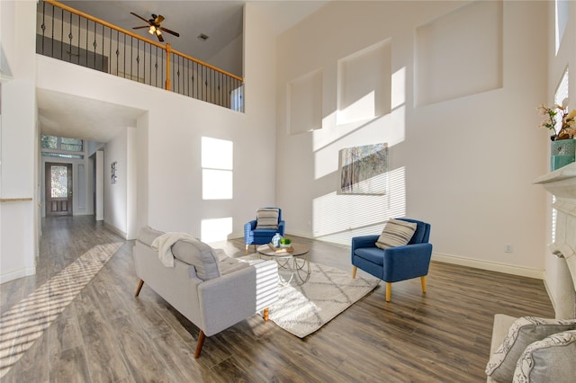 living room with ceiling fan, a towering ceiling, and hardwood / wood-style floors