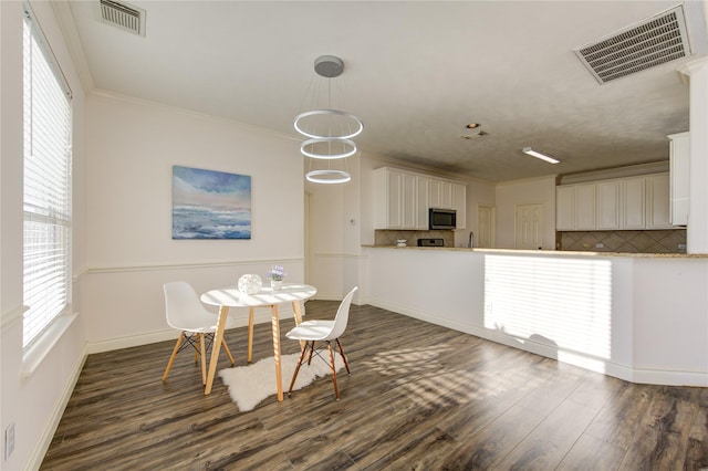 dining space with crown molding, dark hardwood / wood-style flooring, and a chandelier