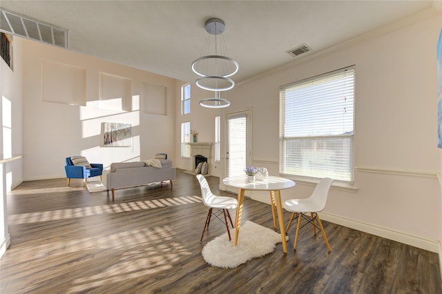 dining space featuring an inviting chandelier, ornamental molding, and dark hardwood / wood-style floors