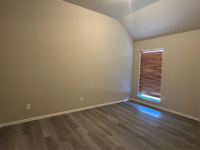 spare room featuring vaulted ceiling and dark hardwood / wood-style floors