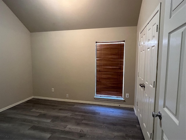 empty room featuring vaulted ceiling and dark hardwood / wood-style floors