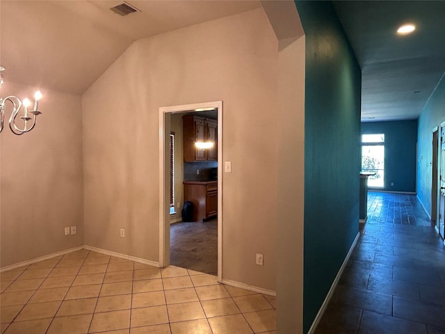 hall featuring vaulted ceiling, light tile patterned floors, and an inviting chandelier