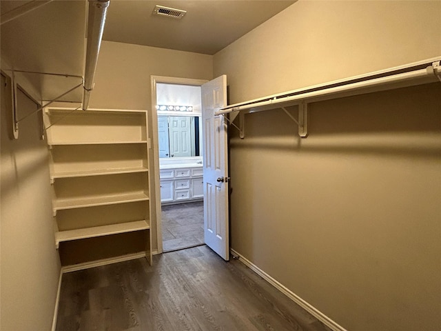 walk in closet with dark wood-type flooring