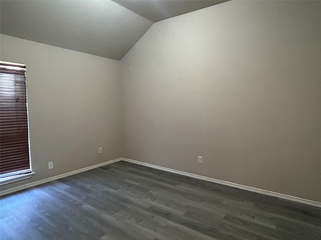 empty room featuring vaulted ceiling and dark wood-type flooring