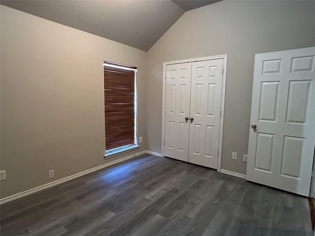 unfurnished bedroom featuring lofted ceiling, a closet, and dark hardwood / wood-style floors