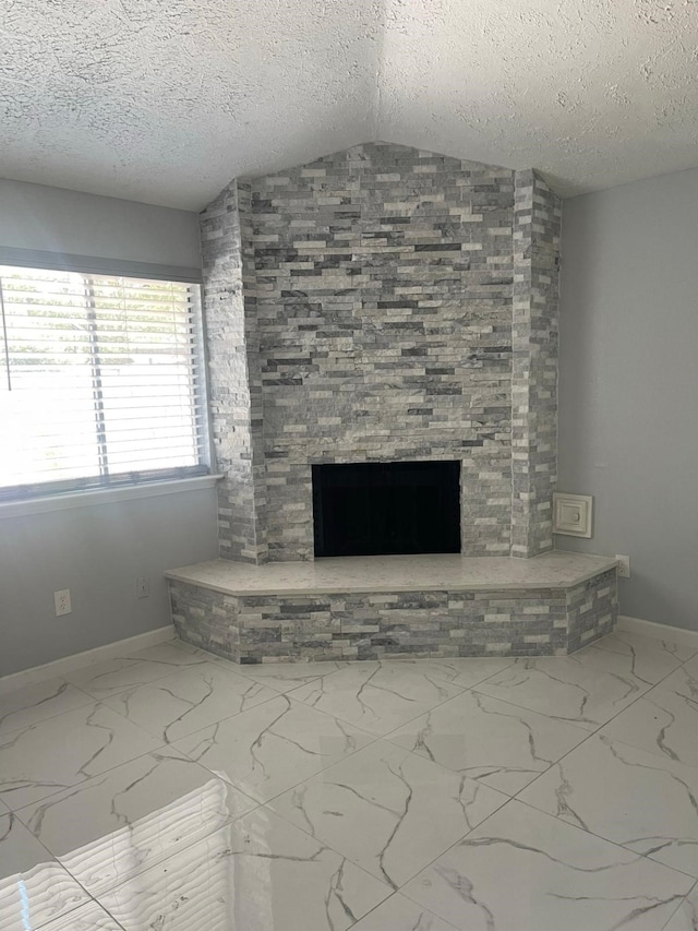 unfurnished living room featuring vaulted ceiling, a stone fireplace, and a textured ceiling